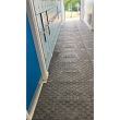 Black plastic ground mats with a raised diamond tread pattern and HERMEQ branding, installed in a hallway beside lockers.