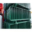 Angled view of green barriers, showing dense packing, welded vertical bars, curved frames and welded joints.