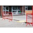 Multiple barriers—red and white—are arranged in a connected line to form a pedestrian or construction safety zone.