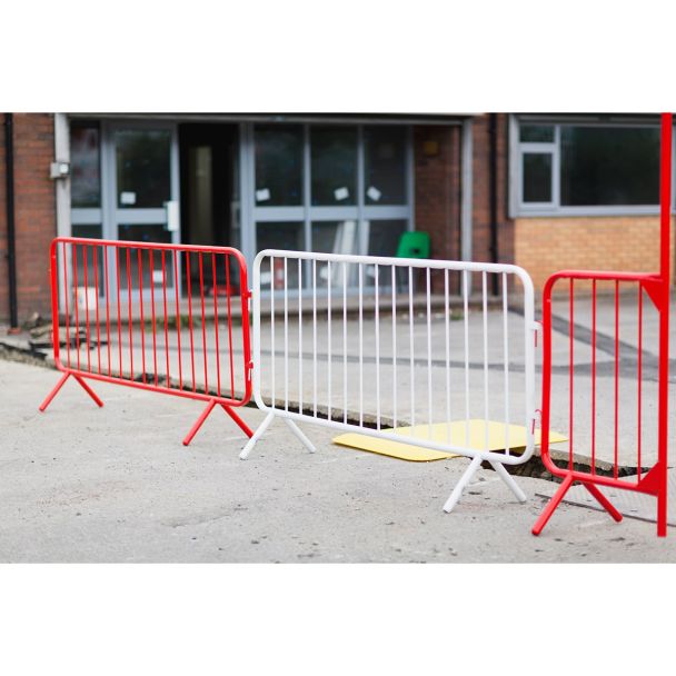 Multiple barriers—red and white—are arranged in a connected line to form a pedestrian or construction safety zone.