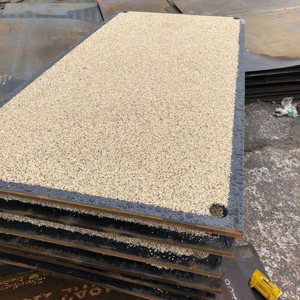Anti-skid trench plates stacked in an industrial yard with bauxite stone non-skid finish for temporary ground protection