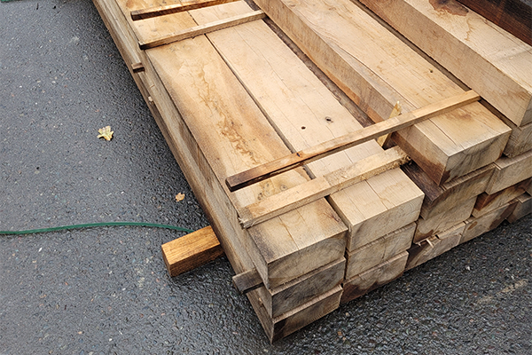 Baulk timbers laid along the base of a scaffold beside a road
